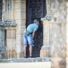 Un hombre observa el interior de la ermita del Mirón desde fuera.