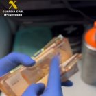 Un agente de la Guardia Civil recuenta un fajo de billetes en un registro.