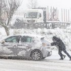 Dos personas empujan un coche durante el paso de la borrasca 'Juan'.