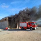 Los bomberos intervienen en la nave ante una densa humareda negra.