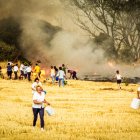 Los vecinos corren con cubos y garrafas mientras un tractorista trata de cortar el avance del fuego en la tarde del 25 de agosto de 2000.