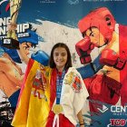 Adriana verde con su medalla de oro, el trofeo, la bandera de España y la de Soria.