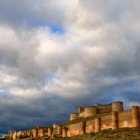 Vista panorámica del castillo de Berlanga de Duero con su doble muralla bajo un cielo dramático al atardecer.