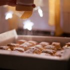 El toque final: una nube de azúcar glas transforma los cochinitos de hojaldre en el postre más esperado de la matanza soriana.