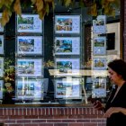 Archivo - Una mujer camina frente a un escaparate de anuncios de viviendas, a 4 de agosto de 2023, en Madrid (España). La compraventa de vivienda en España disminuye un 6,4% interanual por el retroceso de las operaciones sobre los inmuebles usados, según.