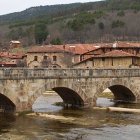 El Puente de los Carreteros, en Salduero, cruza el Duero frente a las tradicionales casonas de piedra de la comarca de Pinares.