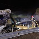 Un bombero trabaja para enfriar el camíón de mercancías peligrosas calcinado tras el accidente.