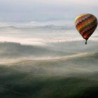 Un globo aerostático surca el cielo sobre un paisaje envuelto en niebla, evocando la experiencia única de contemplar el eclipse desde las alturas