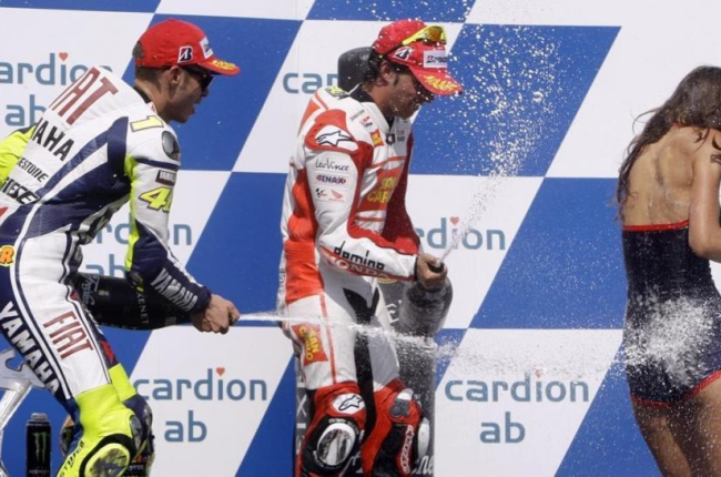 Valentino Rossi y Toni Elias rocían a una azafata con champán en el podio de Brno, en el 2009.-REUTERS / PETR JOSEK