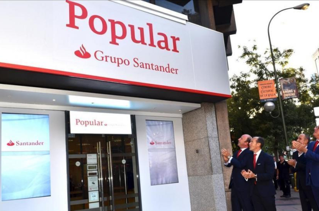 Directivos del Santander ante una de las primeras oficinas del Popular que ya ha adoptado la imagen corporativa del grupo cántabro, en Madrid-EL PERIÓDICO