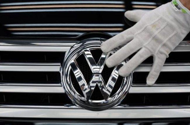 Un empleado coloca el logotipo de Volkswagen a un vehículo.-AFP / RALF HIRSCHBERGER
