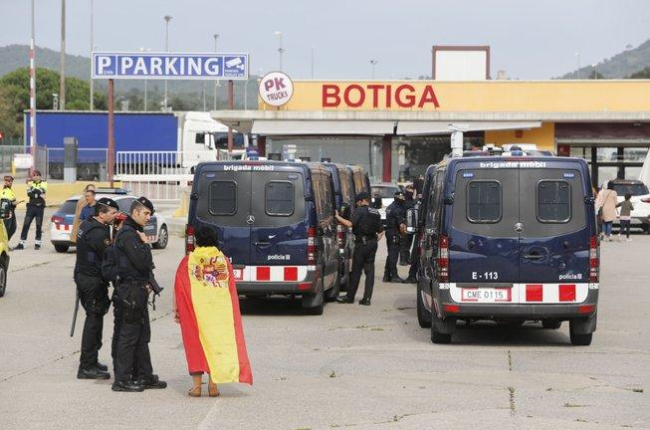 Una mujer con la bandera española habla con los Mossos, en la frontera con la Junquera.-JOAN CASTRO / ICONNA