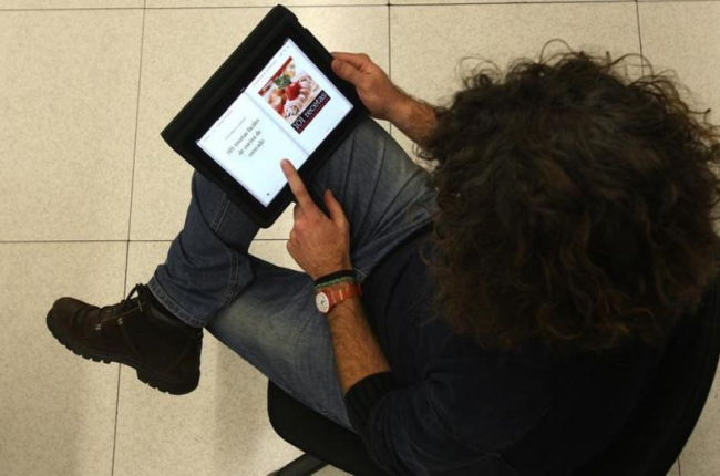 Una lectora, consultando un libro de recetas en una tablet.-ELISENDA PONS