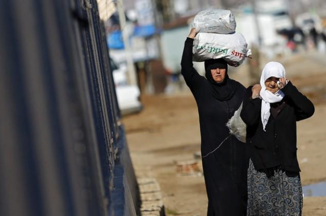 Refugiados sirios trasladan bolsas de alimentos en el paso fronterizo de Öncüpinar, en Kilis, Turquía.-SEDAT SUNA / EFE