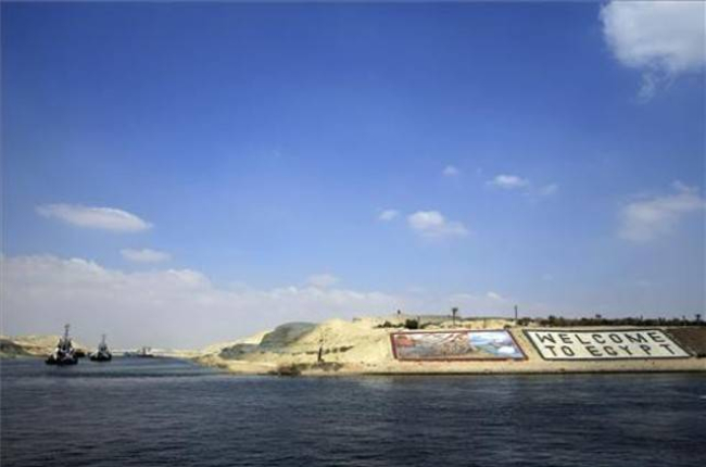 Los barcos empiezan a navegar por el nuevo tramo del canal de Suez, el pasado 13 de junio. Al fondo se lee "Bienvenidos a Egipto".-Foto: AP / HASSAN AMMAR