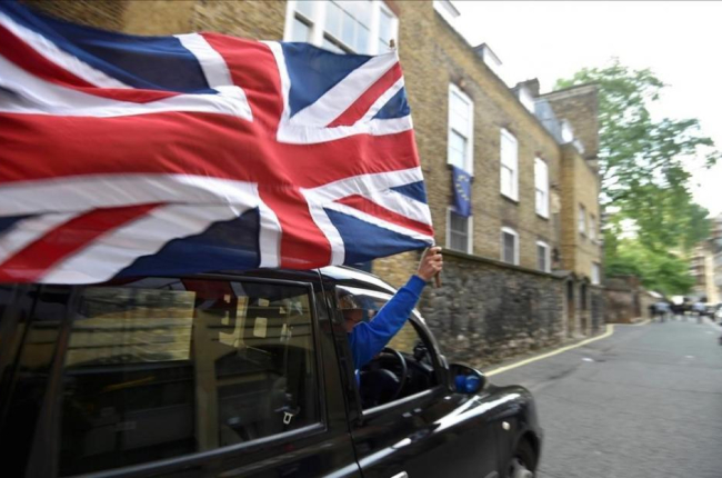 Un motorista con una bandera británica en el centro de Londres.-TOBY MELVILLE / REUTERS