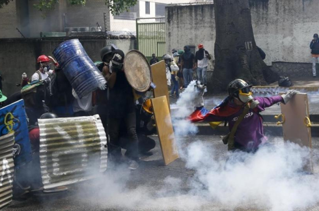 Manifestantes chocan con las fuerzas de seguridad chavistas durante una marcha en Caracas, el 1 de mayo.-AP / ARIANA CUBILLOS