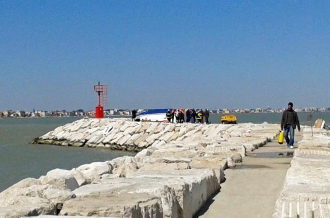 Bomberos y miembros de los servicios de rescate trabajan junto al casco de un barco tras su naufragio en Rimini.-EFE