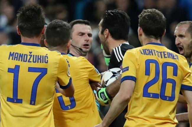 El árbitro Michael Oliver, acosado por los jugadores de la Juve.-REUTERS / SUSANA VERA