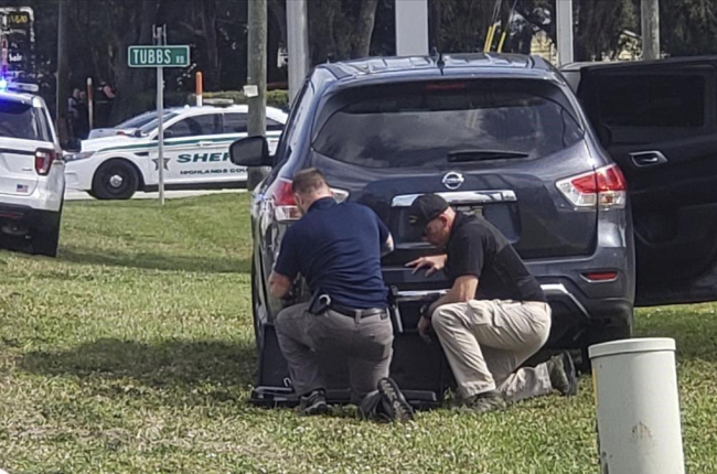 Agentes de policía se protegen tras su vehículo durante el tiroteo en el banco de Florida, este miércoles.-AP