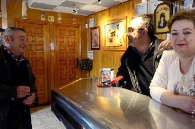 El matrimonio Frías Pérez, tras la barra de su bar a la derecha, reciben la enhorabuena de Juan Gómez, llegado desde Rioseco para darles su felicitación / Á. M.-