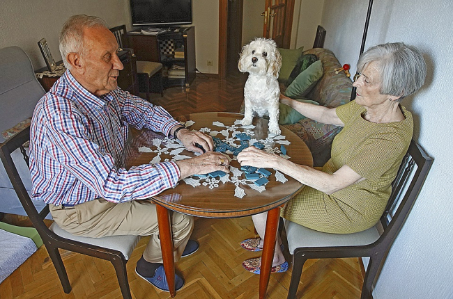 Charo y Fernando, diagnosticado hace cuatro años de Alzheimer, juegan, como cada tarde desde que cerró el centro de la asociación, una de sus partidas de dominó.- J. M. LOSTAU