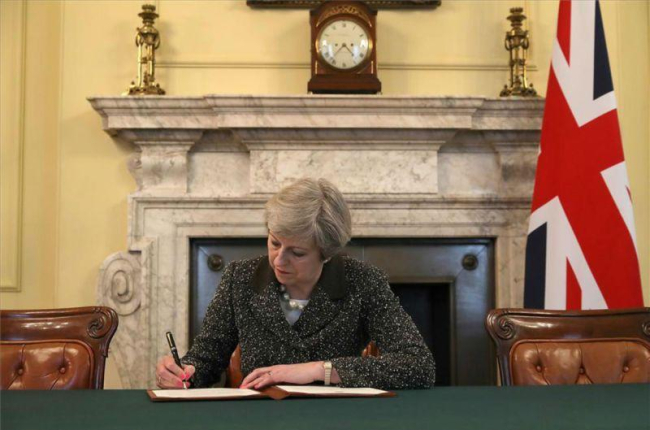 La primera ministra británica, Theresa May, firma la carta con la que arranca el 'brexit'.-REUTERS