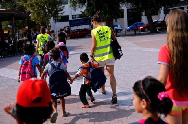 Unos voluntarios acompañan a la escuela a niños refugiados en la isla griega de Chios.-ALKIS KONSTANTINIDIS / REUTERS