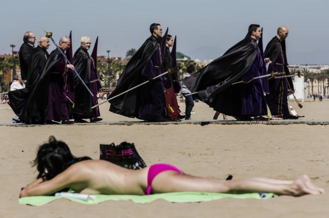 Bañistas y participantes en una procesión de Semana Santa, en la playa de Valencia.-MIGUEL LORENZO