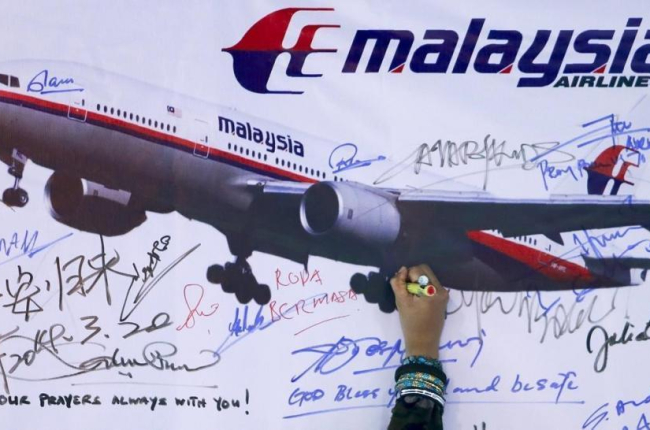 Una mujer escribe un mensaje de solidaridad con los pasajeros del vuelo desaparecido de Malaysia Airlines en Kuala Lumpur en el 2014.-/ SAMSUL SAID (REUTERS)