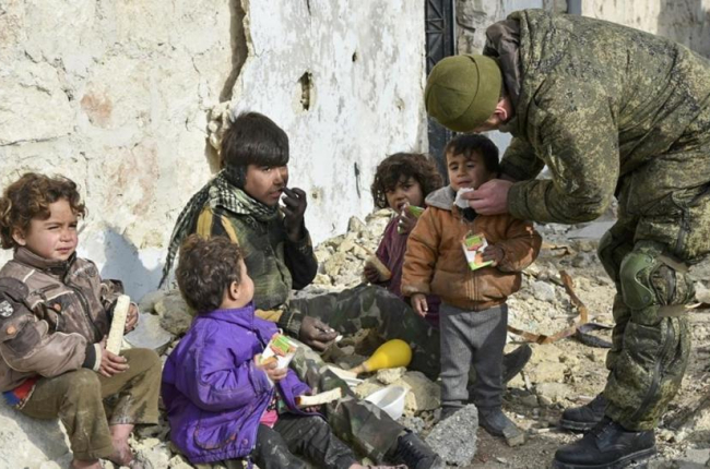 Un militar ruso entrega supuestamente zumo de frutas a niños de Alepo (Siria), en una imagen sin fecha distribuida por el Ministerio de Defensa ruso.-/ AP