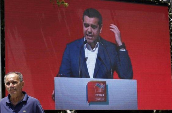 Un hombre pasa frente a una pantalla en la que se proyecta un mitin de Tsipras en Atenas, el pasado 18 de mayo.-YANNIS KOLESIDIS (EFE)