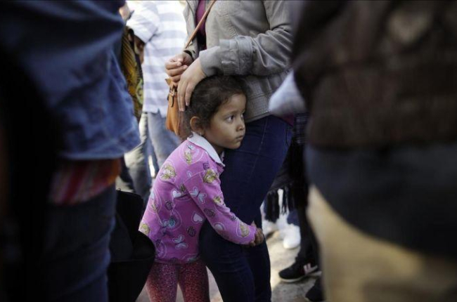 Una niña mexicana con su madre espera con otros inmigrantes en la frontera la respuesta a la solicitud de asilo político en EEUU.-GREGORY BULL (AP)