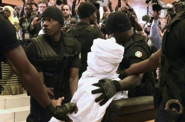 Habré, completamente tapado con una vestimenta blanca, rodeado de policías en el tribunal, en Dakar, este lunes.-Foto: AFP / SEILLOU