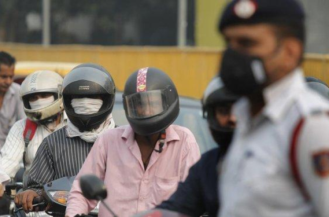 Varios motoristas y un guardia se protegen con mascarillas de la elevada polución, este lunes en Nueva Deli.-MANISH SWARUP (AP)