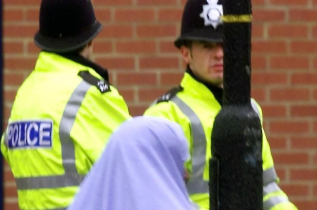 Una mujer musulmana pasa junto a dos policías británicos.-MAX NASH