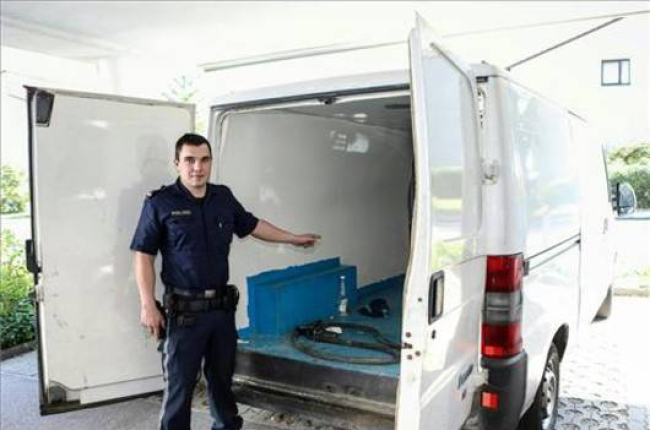 Un agente austriaco muestra la camioneta en la que viajaban los tres niños hallados en estado grave, este sábado, en Braunau (Austria).-DANIEL SCHARINGER / EFE