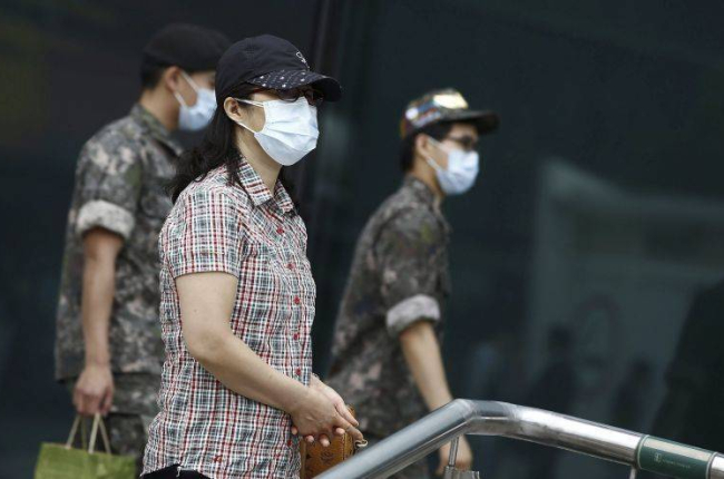 Soldados y civiles pasean con mascarillas por las calles de Seúl.-Foto: EFE