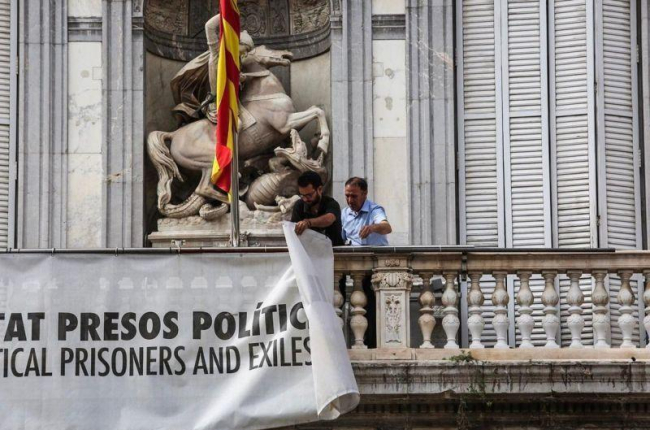 Dos trabajadores de la Generalitat retiran la pancarta que colgaba del Palau.-ÁNGEL GARCÍA