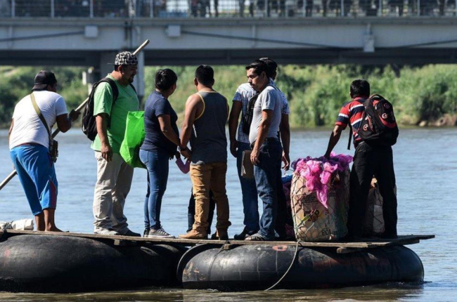 Un grupo de inmigrantes cruza el río Suchiate en unos neumáticos.-ORLANDO SIERRA / AFO