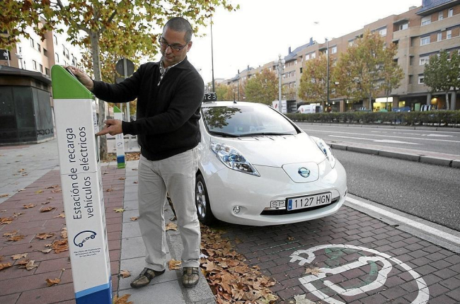 Un hombre utiliza un puesto de recarga de coche eléctrico.-ICAL