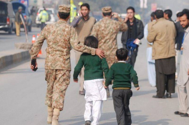 Un soldado paquistaní escolta a dos niños rescatados de la escuela que ha sufrido el ataque en Peshawar.-Foto: REUTERS / KHURAM PARVEZ