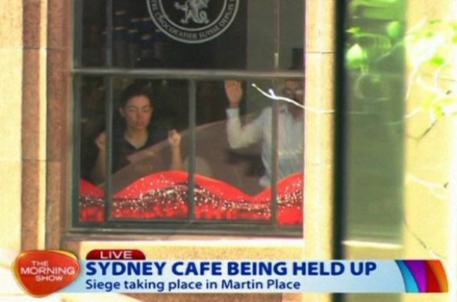 Dos de los rehenes, contra las ventanas del café Lindt Chocolate Cafe, del centro de Sídney, este lunes.-Foto: AP