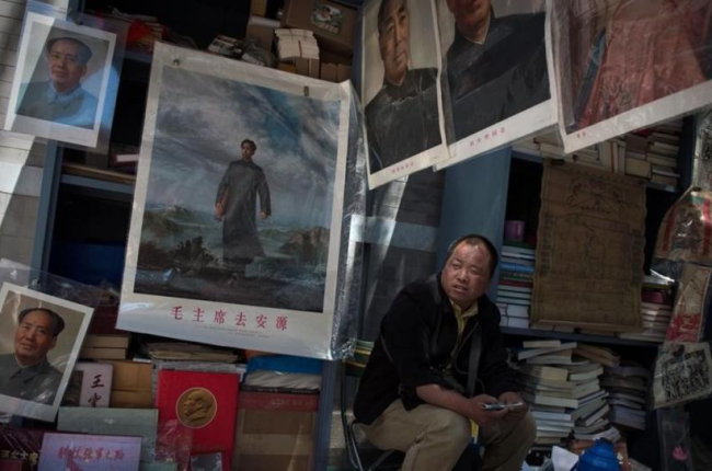 Un comerciante espera la llegada de clientes para vender imágenes y recuerdos de Mao Zedong.-AFP / NICOLAS ASFOURI