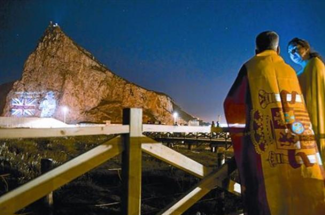 Una pareja mira desde la Línea de la Concepción la proyección de la imagen de Isabel II en el Peñón, en junio del 2012, cuando las autoridades de Gibraltar celebraron el 60º aniversario del ascenso al trono de la reina.-MARCOS MORENO