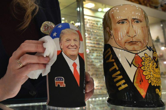 La empleada de una tienda de 'souvenirs' de Moscú saca brillo a las matrioskas de Trump y Putin, a cuatro días de la investidura del primero como presidente de EEUU.-AFP / ALEXANDER NEMENOV