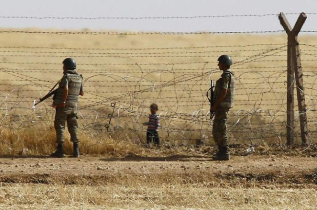 Un niño sirio espera tras las vallas de la frontera para cruzar hacia Turquía cerca de Akcacale (sureste), en el 2015.-REUTERS / OSMAN ORSAL