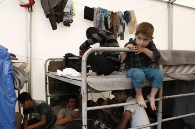 Una familia afgana encuentra refugio dentro de una tienda en un campamento de tránsito al oeste de Atenas.-EFE / YANNIS KOLESIDIS