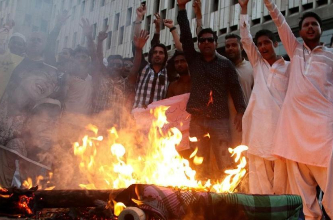 Manifestantes queman una imagen de la líder de facto de Birmania, Aung San Suu Kyi, durante una protesta contra la persecución de los rohinyas, en Karachi (Pakistán), el 17 de septiembre.-EFE