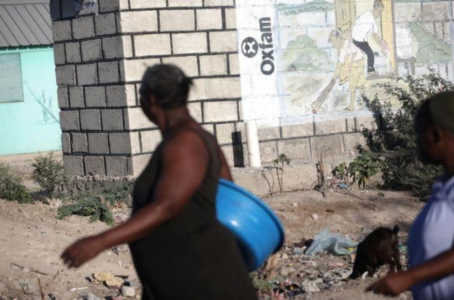Dos mujeres pasan ante un mural de Oxfam en Puerto Príncipe, Haití.-ANDRES MARTINEZ CASARES (REUTERS)